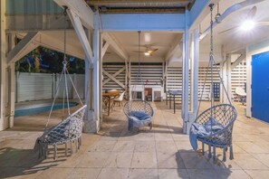 Un espacio exterior cubierto con piscina, sillones colgantes y una mesa de comedor.