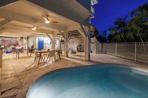 Un espacio al aire libre techado con piscina, mobiliario y una parrilla.