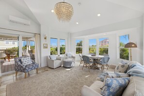 A spacious living area with a high ceiling, a chandelier, and a view of the outside.