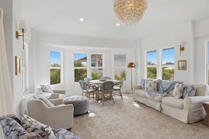 A spacious living area with a dining set, sofas, and a chandelier.