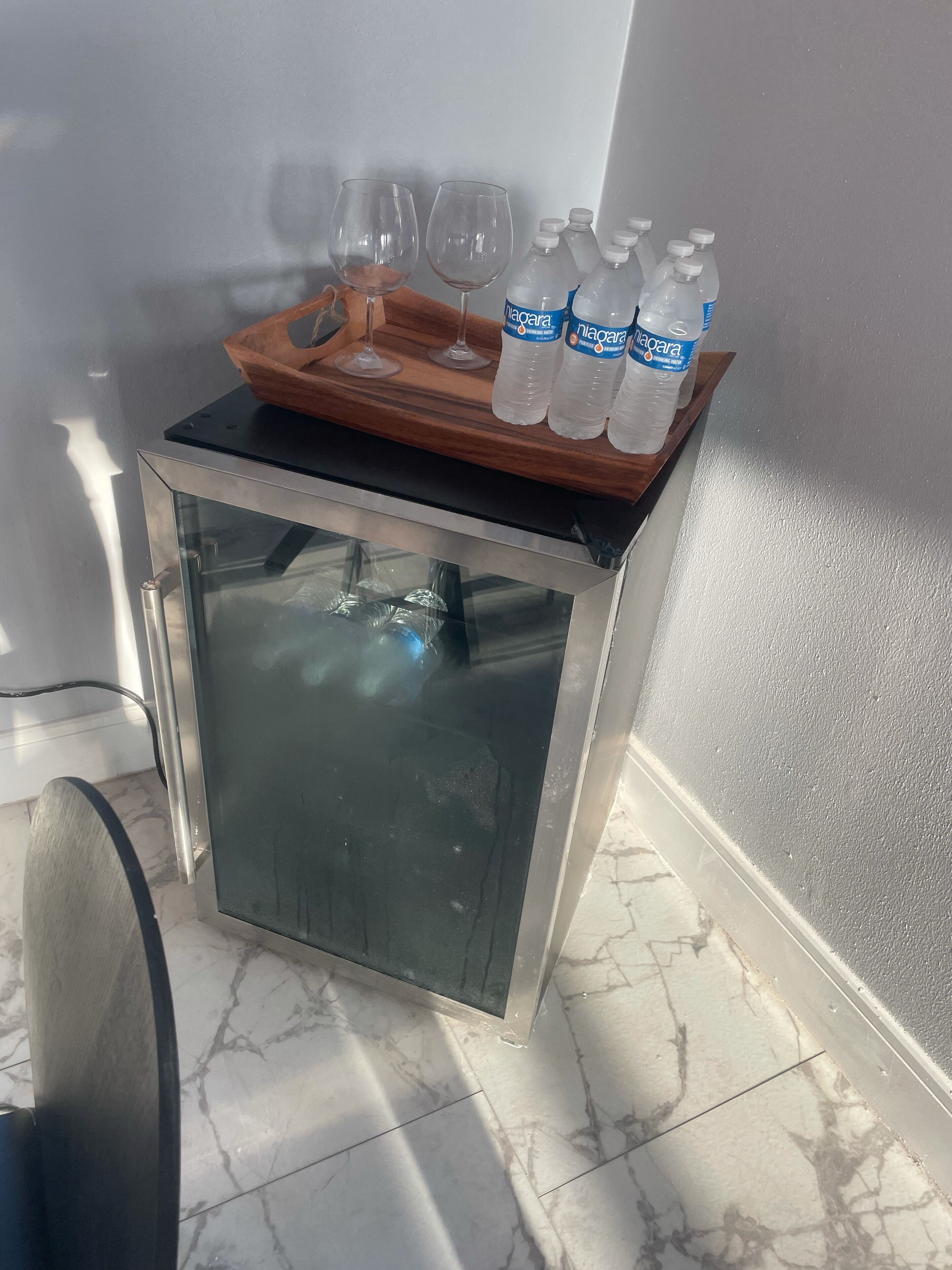 Un mini refrigerador con un juego de botellas de agua y vasos.