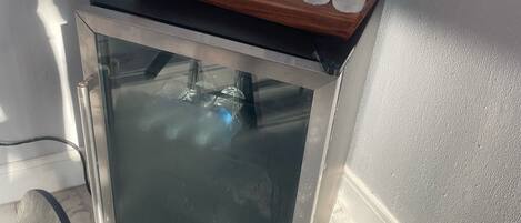 Un mini refrigerador con un juego de botellas de agua y vasos.