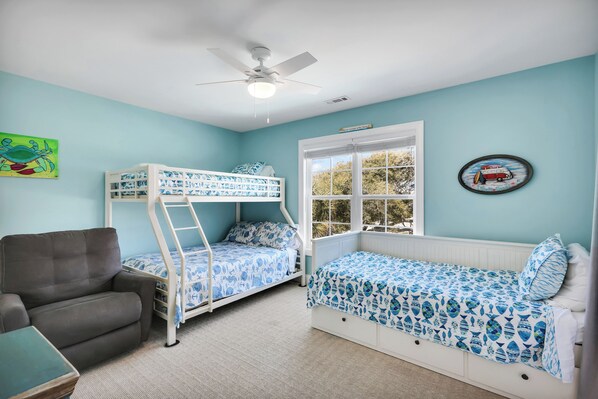 A room with two bunk beds, a desk, a chair, a window with a view, and a ceiling fan. - Sea 2 Sea - 4 Bdrm w/ Pool and New Patio - 1 Minute Walk to Beach (Oak Island)