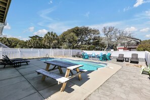 En baghave med swimmingpool, liggestole og et picnicbord.