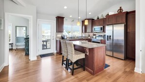 Una cocina moderna con armarios de madera, electrodomésticos de acero inoxidable y una isla central con una silla de mimbre.