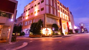 A multi-story hotel with a modern design, featuring a prominent entrance with a decorative archway and illuminated signage. - Deigo Hotel (Okinawa)