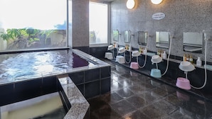 A modern bathroom with a large hot tub, multiple sinks with mirrors, and a view of greenery outside. - Deigo Hotel (Okinawa)