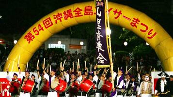 A group of people in traditional attire performing under a large arch with Japanese text.