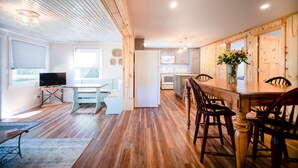 Eine geräumige Küche mit Holzboden, einem Essbereich mit Holztisch und -stühlen, einer eingebauten Mikrowelle und einem Kühlschrank.