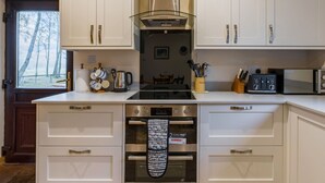 Una cocina moderna con armarios blancos, horno integrado y cafetera.