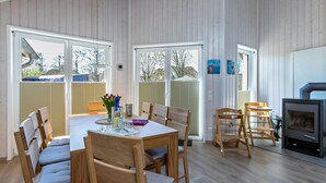 A spacious room with a wooden dining table, chairs, a fireplace, and large windows.