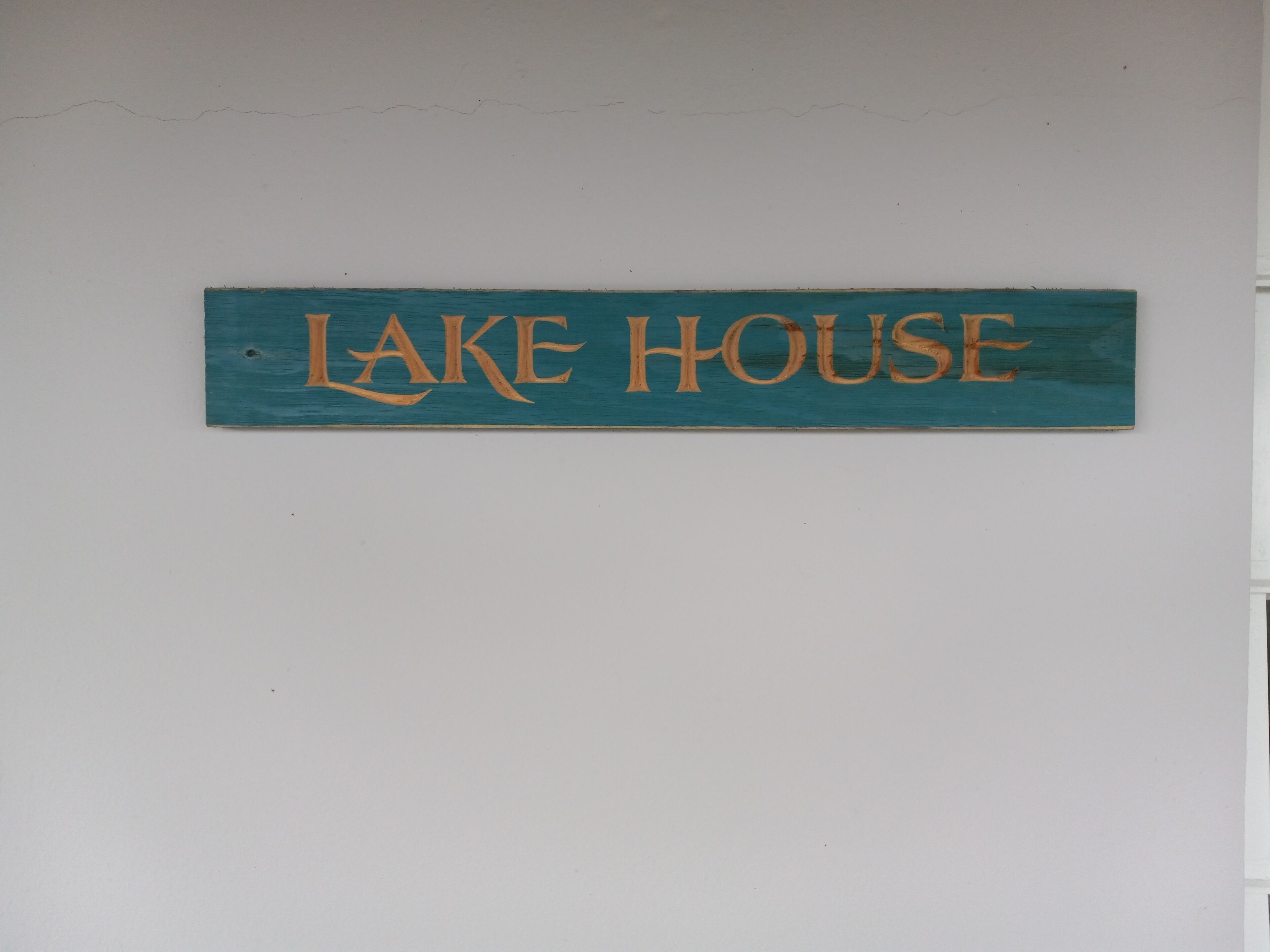 Ein hölzernes Schild mit der Aufschrift 'LAKE HOUSE' an einer Wand befestigt.