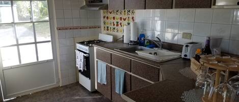 Une cuisine équipée d’une cuisinière à gaz, d’un four, d’un évier et d’une fenêtre.