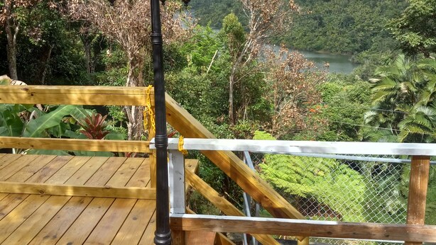 A wooden deck with a metal railing overlooking a lush valley.