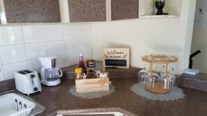 A kitchen with a granite countertop, a coffee maker, a toaster, a sign with a WiFi password, and a small plant on a shelf.