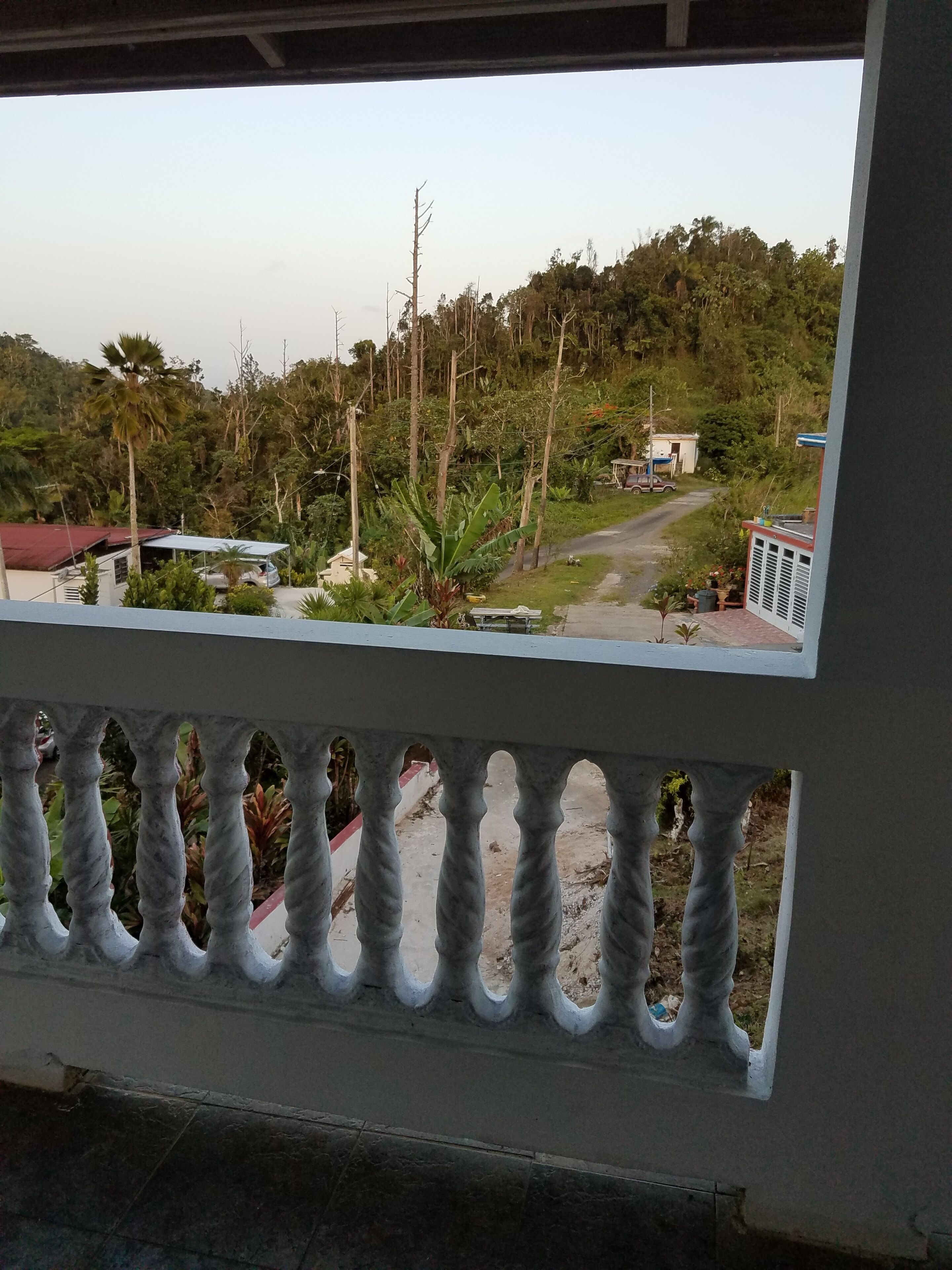 Un balcon donnant sur un paysage rural, avec une route et de la végétation.