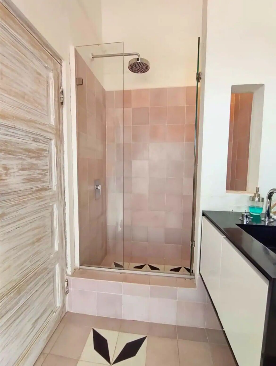 A bathroom with a shower, a sink, and a mirror.