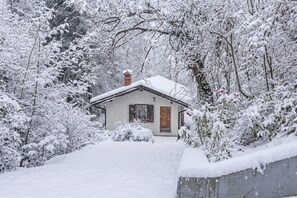 A house with a sloped roof, surrounded by snow-covered trees and a snow-covered ground. - House By The Stream in Soča Valley, Kanal ob Soči, Slovenia (Kanal ob Soči)