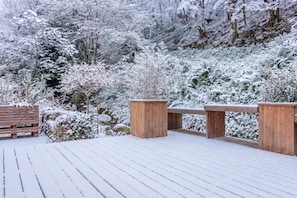 A wooden deck with benches and a wooden fence, surrounded by snow-covered trees and shrubs. - House By The Stream in Soča Valley, Kanal ob Soči, Slovenia (Kanal ob Soči)