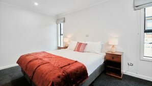 A hotel room with a bed, two bedside tables with lamps, a window with a view, and a ceiling light. - Star View - 1 Bedroom suite C (Lake Tekapo)
