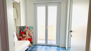 A room with a white sofa, a painting, and a blue tiled floor.