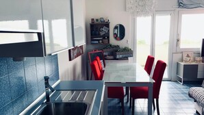 A modern kitchen with a built-in sink, a dining area with red chairs, and a large window providing natural light.