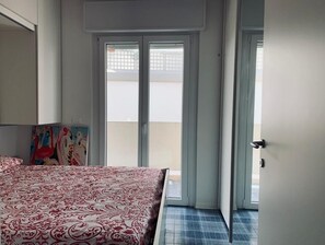Quarto com uma cama, uma porta que dá para uma varanda e um quadro na parede.
