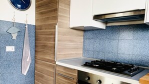 A kitchen with wooden cabinets, a gas stove, and a blue tiled backsplash.