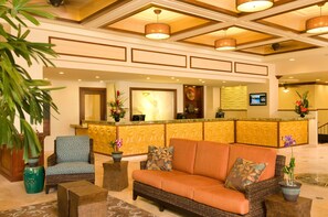 Welcome to our lobby, featuring a reception desk, comfortable seating area, and a beautiful potted plant.