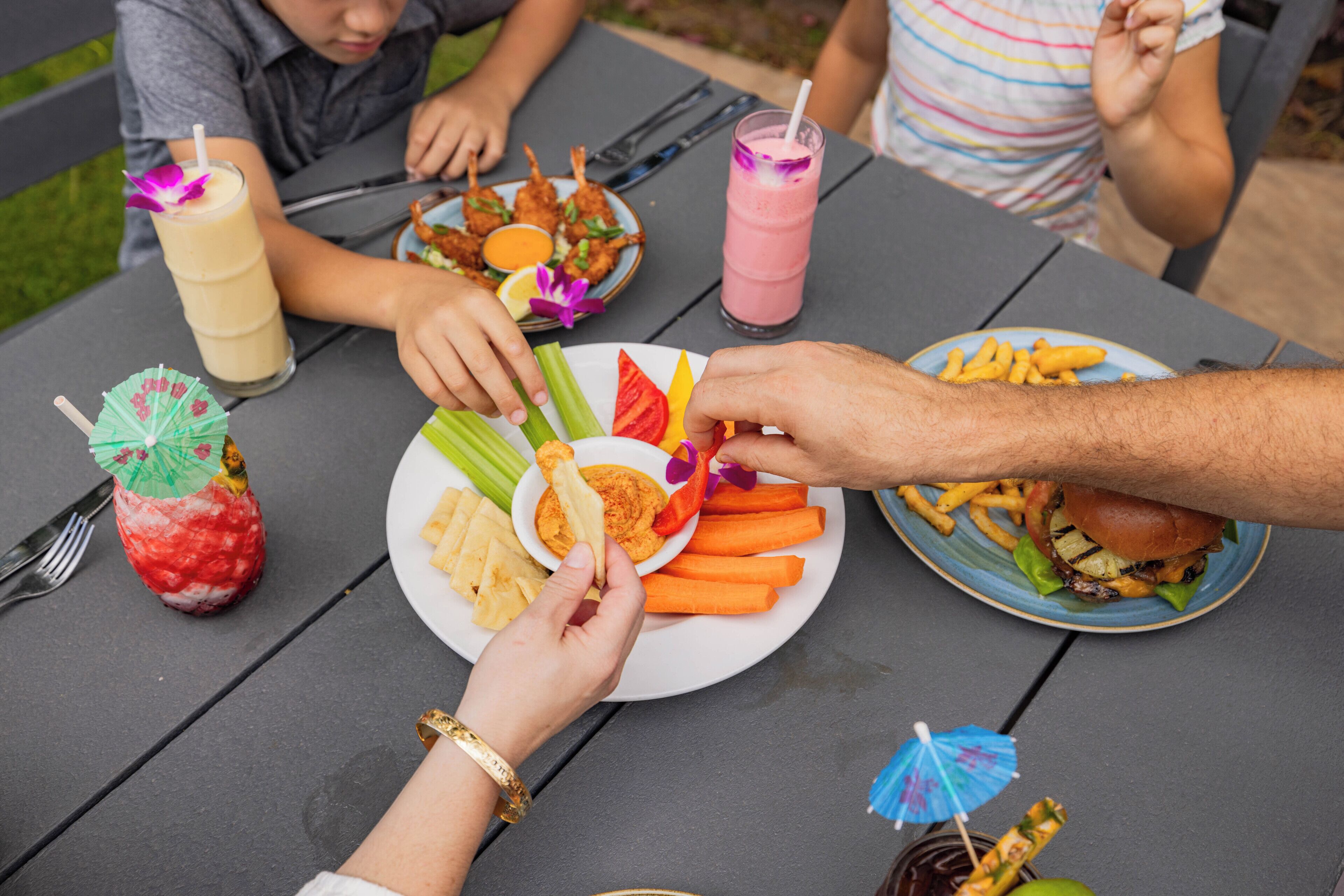 Una mesa de comedor con platos de comida, bebidas y un pequeño adorno con forma de paraguas.