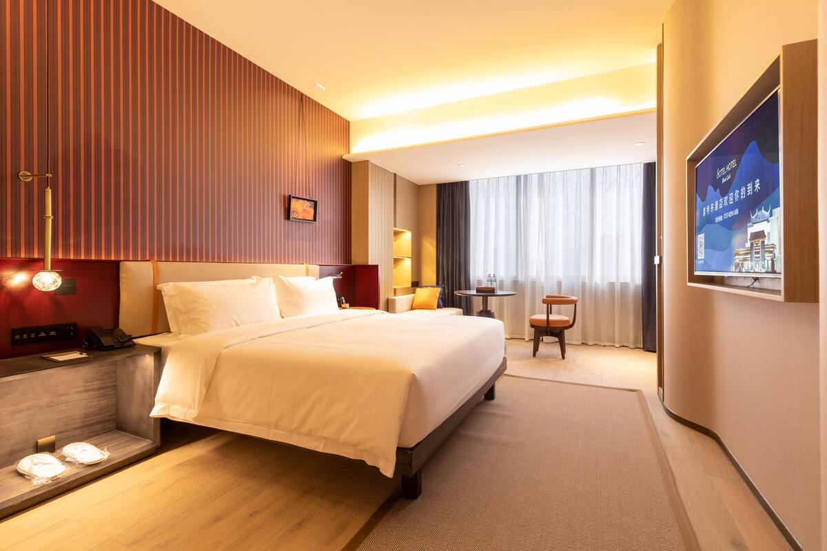 Una habitación de hotel con una cama grande, mesitas de noche, un escritorio y una silla.