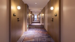 A hotel hallway with wooden walls, numbered doors, and patterned carpet. - Foshan Xinxuangong Hotel  (Foshan)