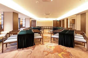 Conference room with a long table and rows of chairs, surrounded by shelves and wooden paneling.