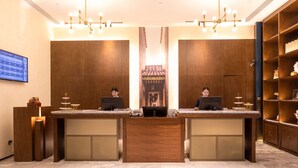 A reception desk with two computer stations, a digital display, and a traditional decorative screen. - Foshan Xinxuangong Hotel  (Foshan)