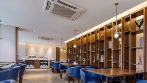 A modern restaurant interior with wooden bookshelves, blue chairs, and a central dining table. - Foshan Xinxuangong Hotel  (Foshan)