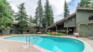 A swimming pool with a brick deck, surrounded by buildings with a green facade and wooden deck areas. - Walk to Ski, Near Canyon Lodge, Quiet Getaway 512 (Mammoth Lakes)