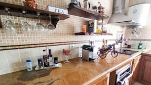 Una cucina con rivestimento in piastrelle, una dispensa per tè e diversi elettrodomestici.