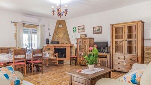Un soggiorno con camino, mobili in legno, un'area pranzo con sedie e un tavolo, e una televisione.