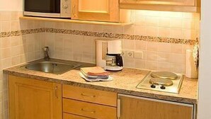 Cafetera o tetera, frigorífico, microondas y placa de cocina