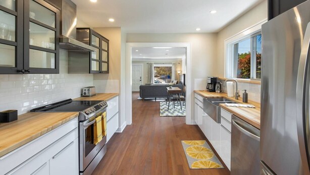 Una cocina moderna con electrodomésticos de acero inoxidable, encimera de madera y vista al área de estar.