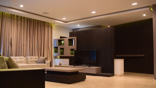 A modern living room with a sofa, a coffee table, a flat-screen TV, and built-in shelving.