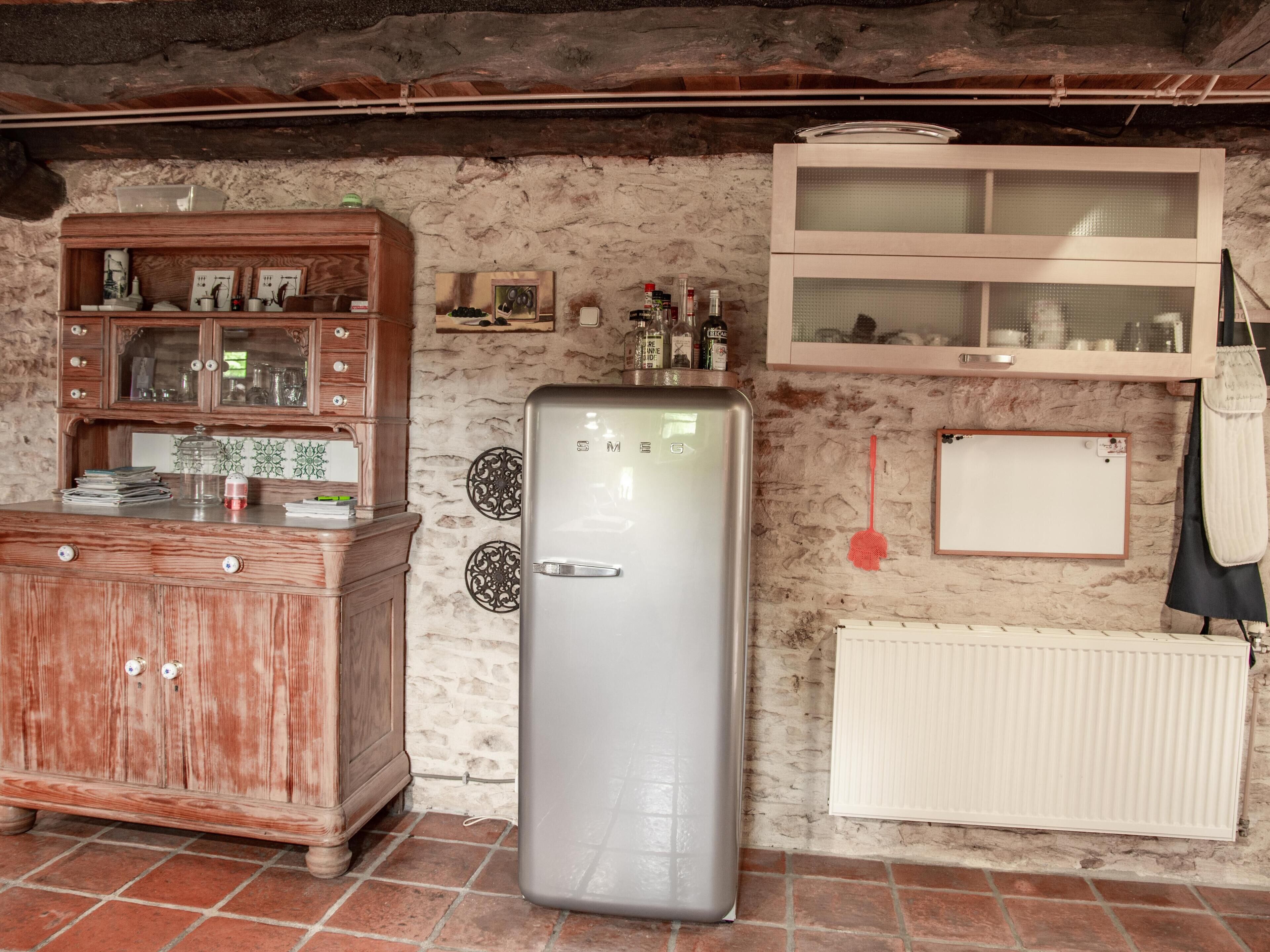 Une cuisine avec des meubles en bois, un réfrigérateur en acier inoxydable, un crédence en carrelage blanc et un radiateur blanc.