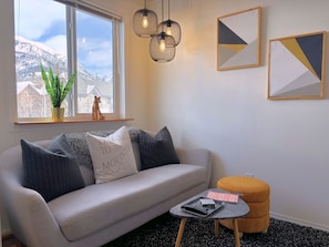 Un salon avec un canapé, une petite table, une plante en pot et des œuvres d’art accrochées au mur.