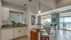 A spacious kitchen with white cabinetry, a marble countertop, and a large window overlooking the ocean. - New! Stunning Ocean View Penthouse Condo at Ocean Dunes Tower I, $300 FREE Activities Daily! (Myrtle Beach)