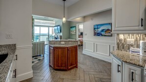 A spacious kitchen with a large island, wooden cabinets, and a herringbone floor pattern. - New! Stunning Ocean View Penthouse Condo at Ocean Dunes Tower I, $300 FREE Activities Daily! (Myrtle Beach)