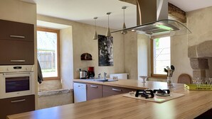 Una cucina moderna con piano di lavoro in legno, forno integrato e lampade a sospensione.