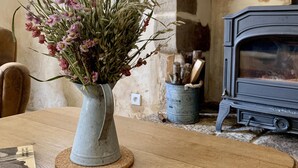 Un tavolo di legno con un vaso di fiori, un caminetto decorato con una mezzaluna e un vecchio fornello.