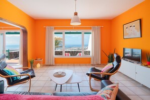 A room with a large window, a television, and a sofa.