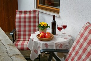 Ein Tisch mit kariertem Tischtuch, einer Obstschale, einer Weinflasche und zwei Weingläsern.