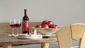 A wooden table with a bottle of wine, glasses, apples, cheese, and crackers. - Apartment "Langeshof - Morgensonne" with Mountain View, Balcony & Garden (Kuens bei Meran, Südtirol - Italien)